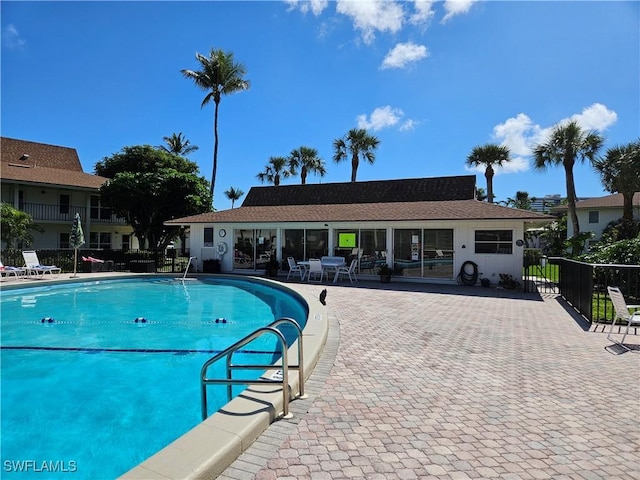 community pool with a patio area and fence