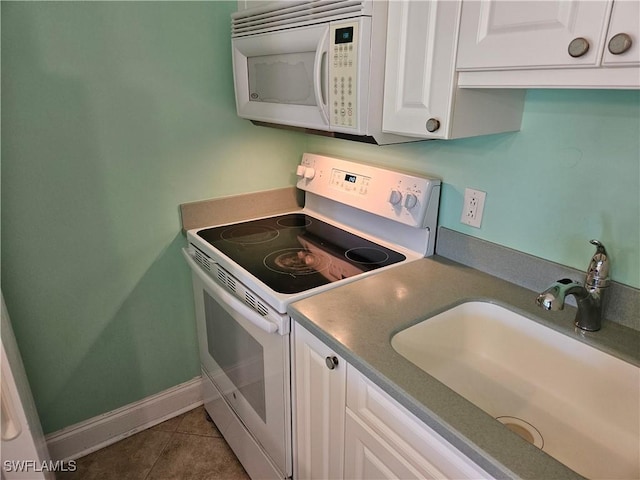 kitchen with baseboards, tile patterned floors, white appliances, white cabinetry, and a sink