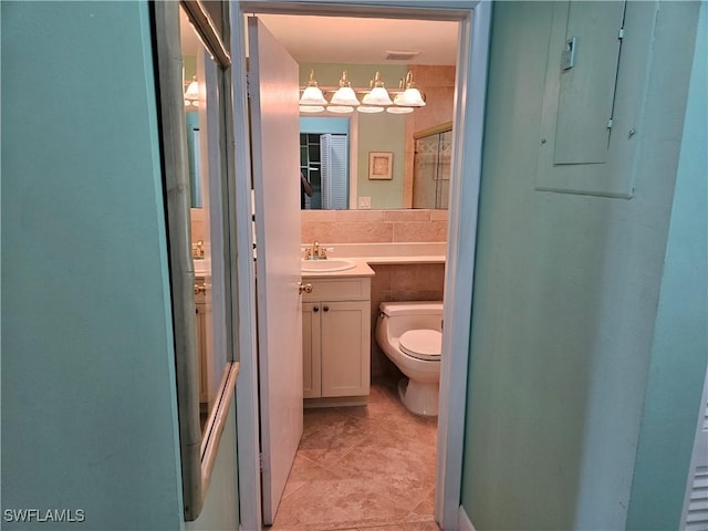 bathroom featuring vanity, visible vents, tile walls, toilet, and tile patterned floors