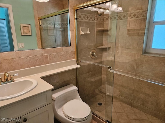 bathroom with a shower stall, vanity, tile walls, and toilet