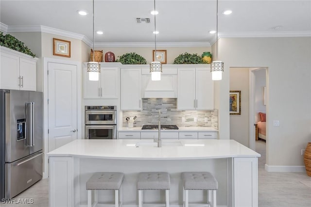 2720 Amaranda Ct, Naples, FL 34114 - kitchen featuring stainless steel appliances, an island with sink, white cabinets, and decorative light fixtures