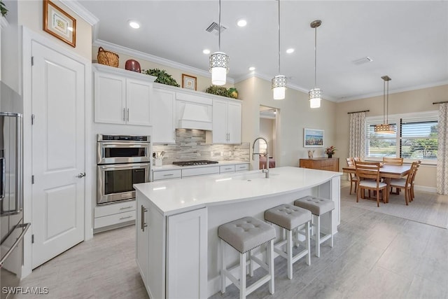 2720 Amaranda Ct, Naples, FL 34114 - kitchen featuring decorative light fixtures, a center island with sink, white cabinets, and appliances with stainless steel finishes