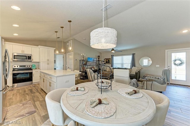 dining area with ceiling fan, lofted ceiling, and light hardwood / wood-style flooring