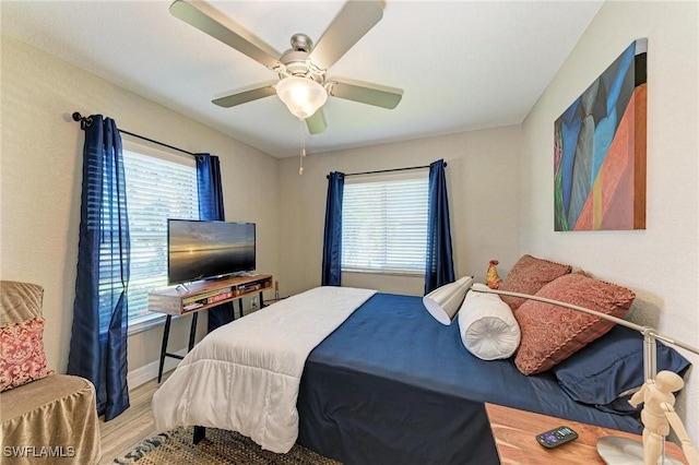 bedroom with multiple windows, light hardwood / wood-style flooring, and ceiling fan