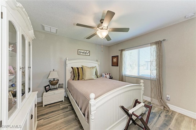 bedroom with ceiling fan, hardwood / wood-style floors, and a textured ceiling