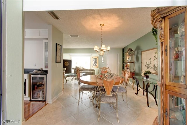 dining room featuring visible vents, beverage cooler, light tile patterned floors, a notable chandelier, and a textured ceiling