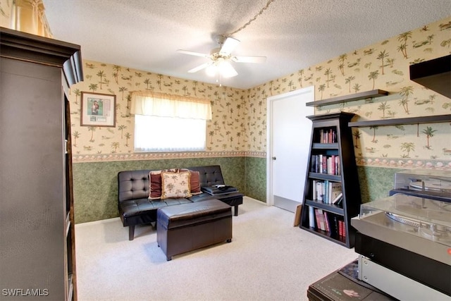 living area featuring a textured ceiling, carpet, a ceiling fan, and wallpapered walls