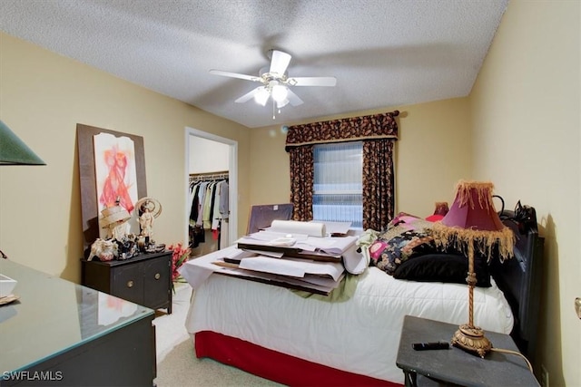 bedroom featuring a walk in closet, ceiling fan, carpet, a closet, and a textured ceiling