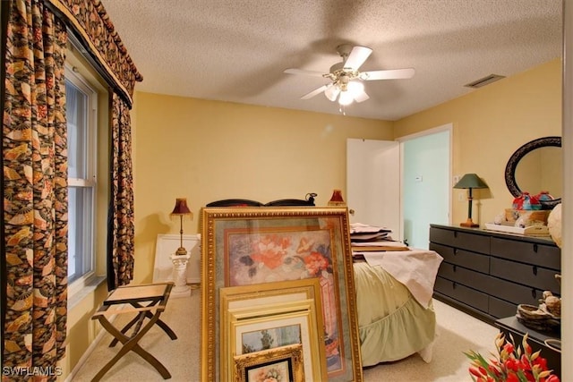 bedroom with ceiling fan, carpet flooring, visible vents, and a textured ceiling