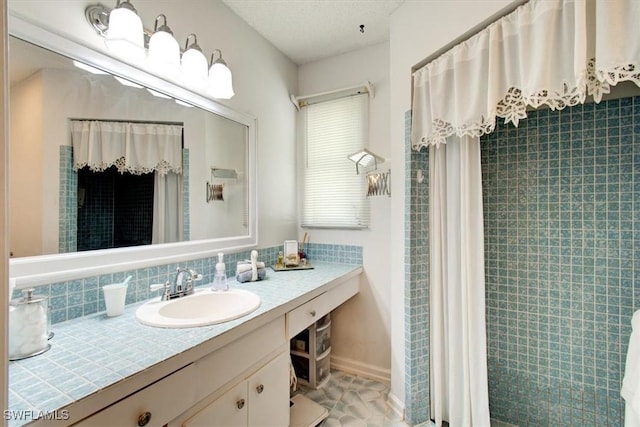 bathroom with vanity, curtained shower, baseboards, and a textured ceiling