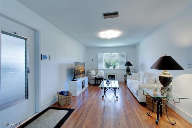 living area with wood finished floors, visible vents, and baseboards