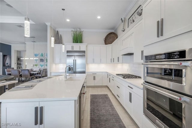 kitchen featuring appliances with stainless steel finishes, pendant lighting, a large island with sink, and white cabinets