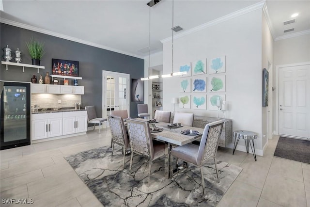 dining room featuring indoor bar, beverage cooler, a towering ceiling, french doors, and ornamental molding