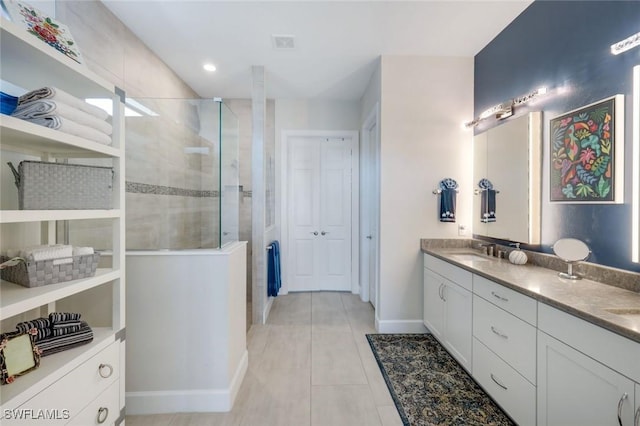 bathroom with tile patterned flooring, vanity, and a tile shower