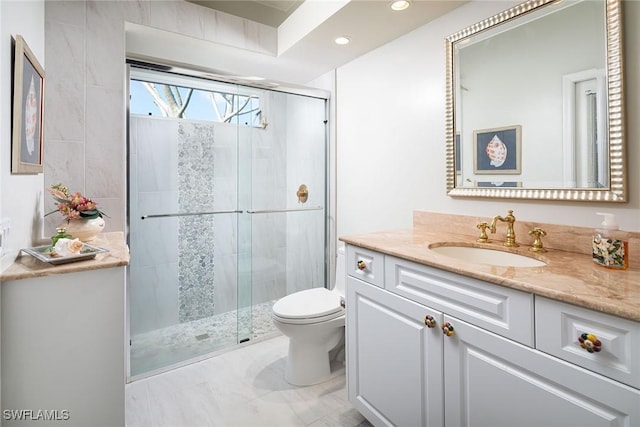 bathroom with vanity, a shower with door, and toilet