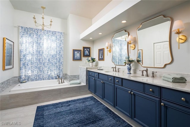 bathroom with tiled tub, vanity, tile patterned flooring, and a notable chandelier