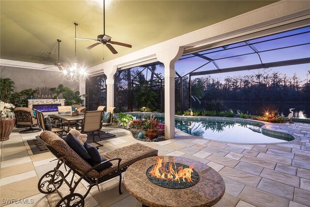 patio terrace at dusk with ceiling fan, an outdoor fire pit, and glass enclosure