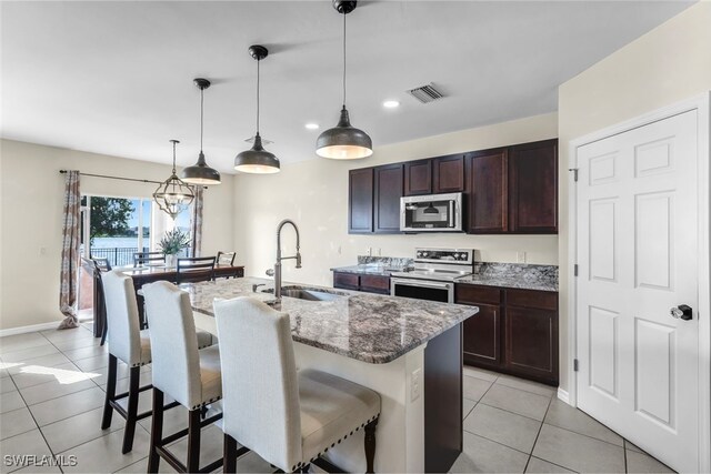 2628 Manzilla Ln, Cape Coral, FL 33909 - kitchen with stainless steel appliances, a sink, light tile patterned flooring, a breakfast bar, and light stone countertops