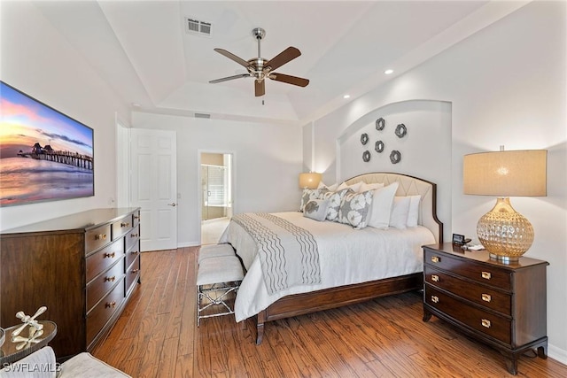 bedroom featuring ceiling fan, wood-type flooring, and a tray ceiling
