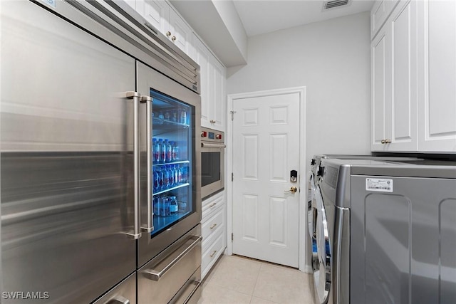 laundry area featuring cabinets, washing machine and dryer, and light tile patterned flooring