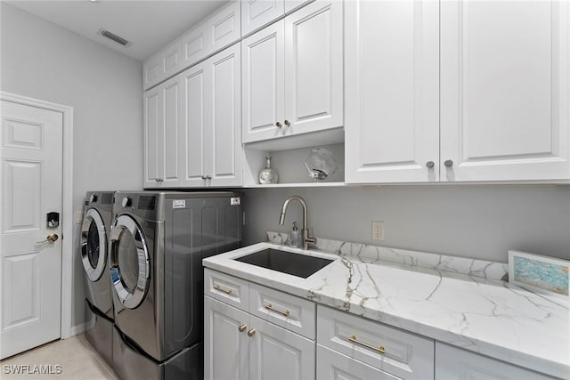 clothes washing area featuring light tile patterned flooring, cabinets, washer and clothes dryer, and sink