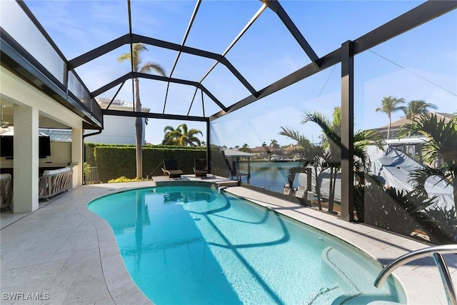 view of pool with a patio, a water view, an outdoor bar, and a lanai