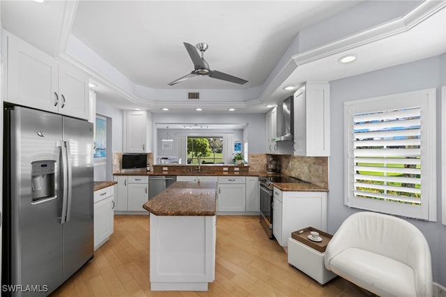 kitchen featuring stainless steel appliances, light hardwood / wood-style floors, backsplash, white cabinetry, and dark stone countertops