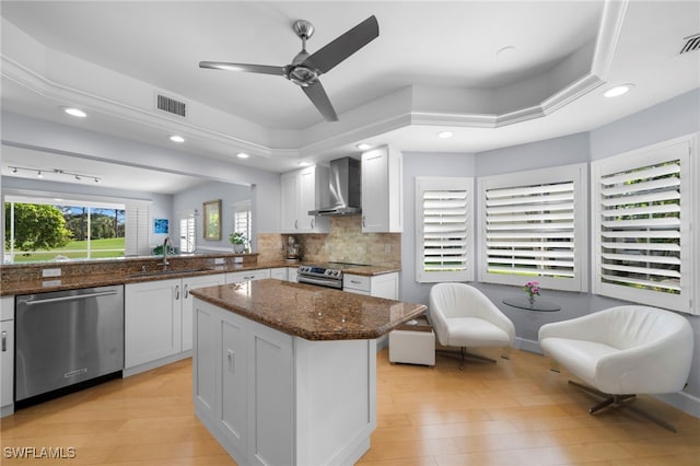 kitchen with white cabinetry, appliances with stainless steel finishes, sink, and wall chimney exhaust hood