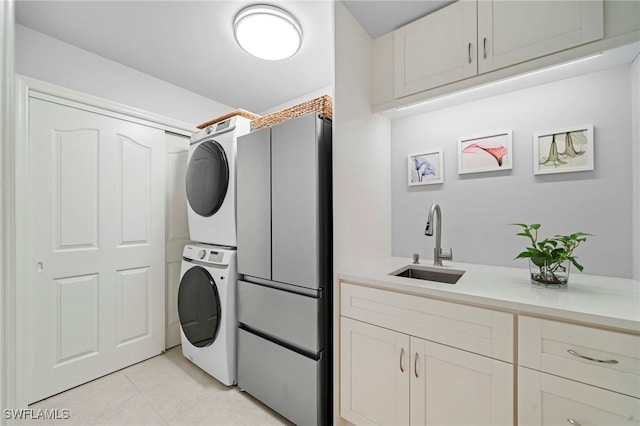 washroom with light tile patterned flooring, sink, stacked washer / drying machine, and cabinets