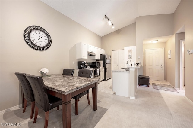dining area featuring high vaulted ceiling, baseboards, and light colored carpet