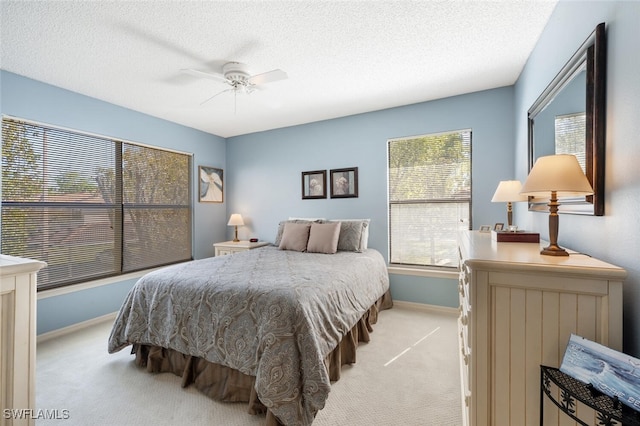 bedroom with light carpet, baseboards, a ceiling fan, and a textured ceiling