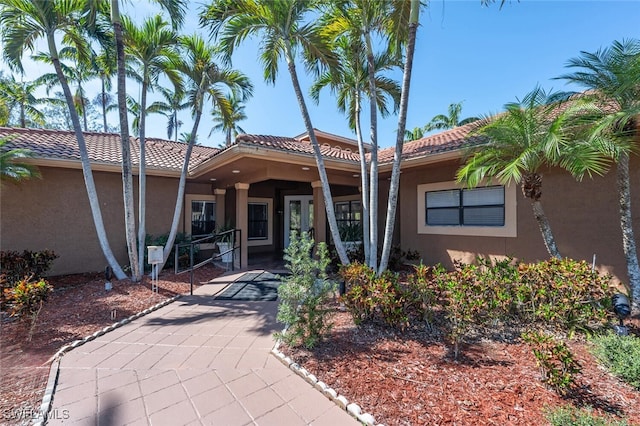 exterior space featuring a tile roof and stucco siding