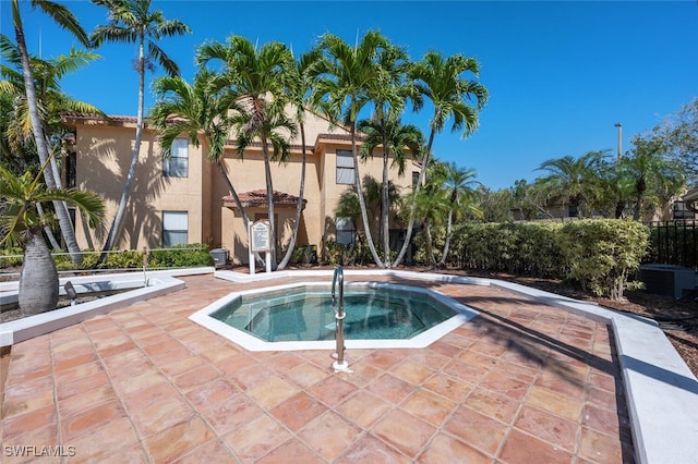view of pool with a community hot tub and fence