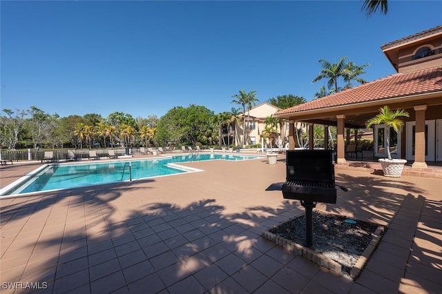 community pool with fence and a patio area