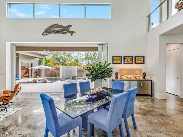 dining room featuring a towering ceiling and concrete flooring