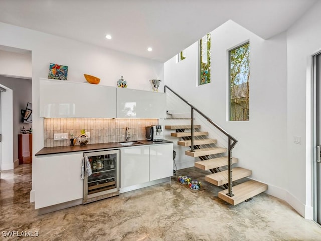 bar featuring white cabinets, tasteful backsplash, sink, and wine cooler