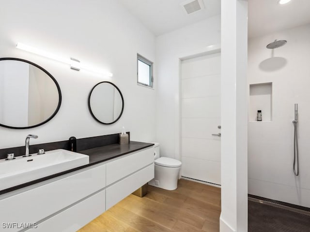 bathroom featuring vanity, hardwood / wood-style floors, a shower, and toilet