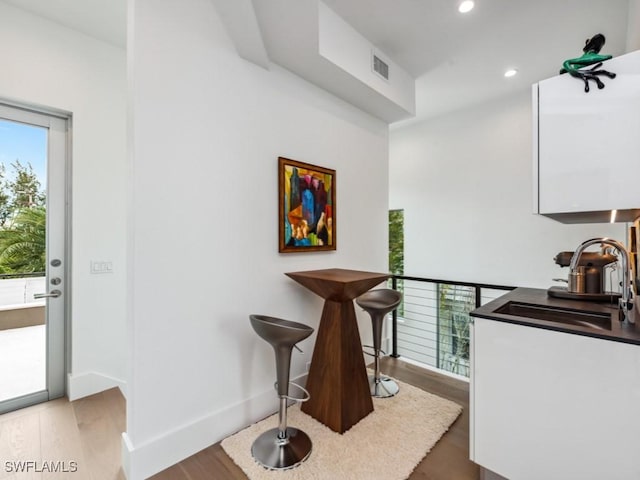 bar with sink and light hardwood / wood-style floors