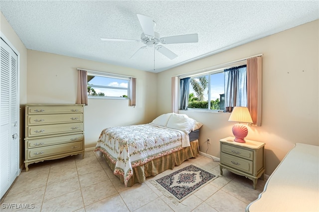 tiled bedroom featuring multiple windows, a closet, and a textured ceiling