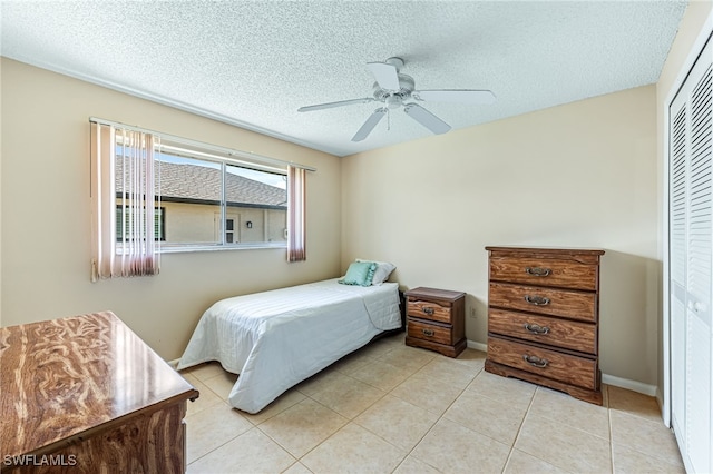 tiled bedroom with ceiling fan, a closet, and a textured ceiling