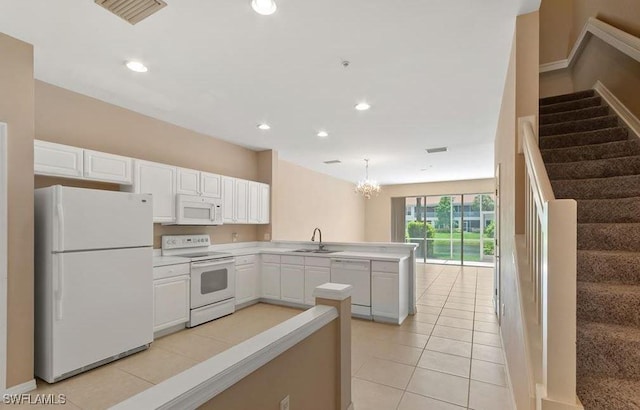1172 Oxford Ln Unit 27, Naples, FL 34105 - kitchen with visible vents, white cabinets, a sink, white appliances, and a peninsula