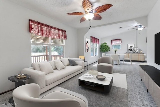 carpeted living area with lofted ceiling, ceiling fan, and a textured ceiling