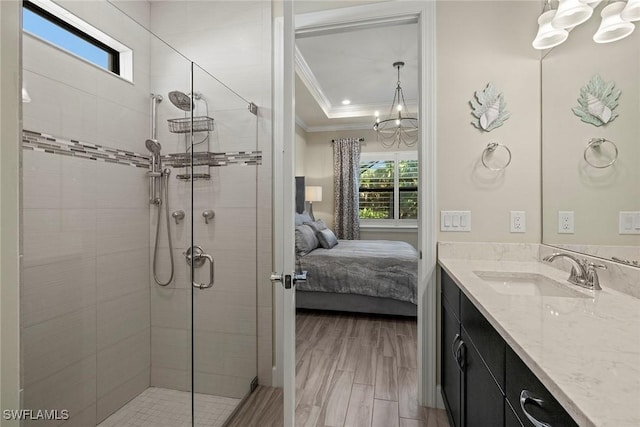 bathroom with wood-type flooring, vanity, an enclosed shower, a raised ceiling, and crown molding