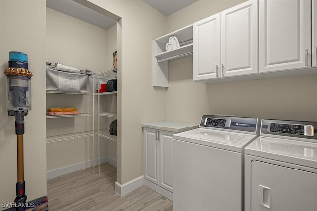 laundry room featuring independent washer and dryer, light hardwood / wood-style floors, and cabinets