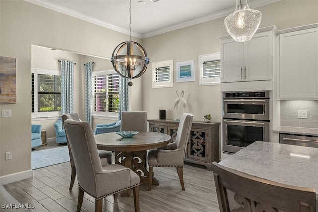 dining space featuring crown molding, an inviting chandelier, and light wood-type flooring