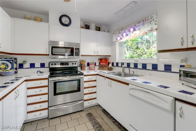 kitchen featuring sink, white cabinetry, pendant lighting, stainless steel appliances, and decorative backsplash