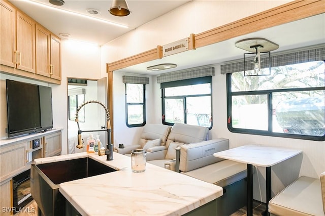 kitchen featuring sink, light stone counters, and light brown cabinetry