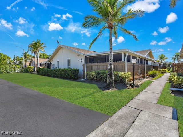 view of front of home featuring fence, a front lawn, and stucco siding