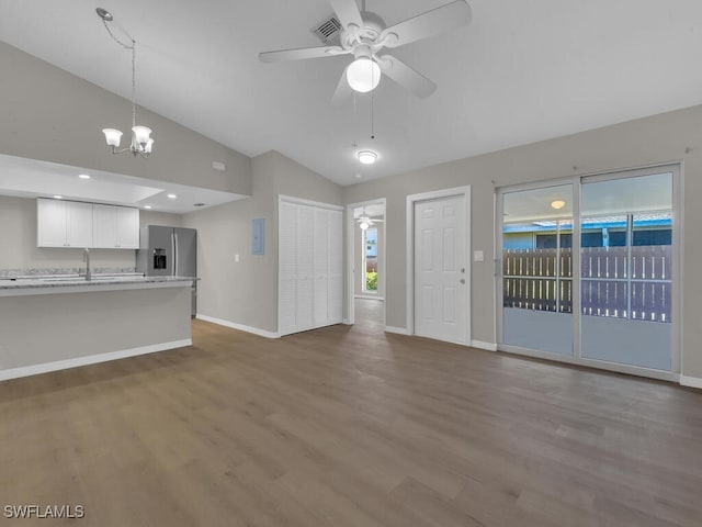 unfurnished living room with vaulted ceiling, wood finished floors, plenty of natural light, baseboards, and ceiling fan with notable chandelier