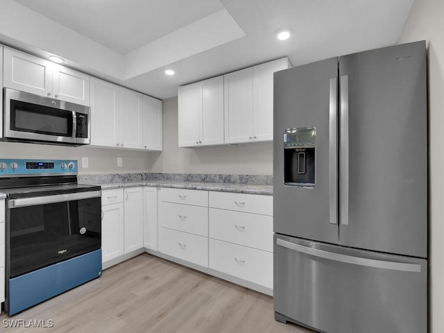 kitchen with recessed lighting, stainless steel appliances, white cabinets, light wood-type flooring, and light stone countertops